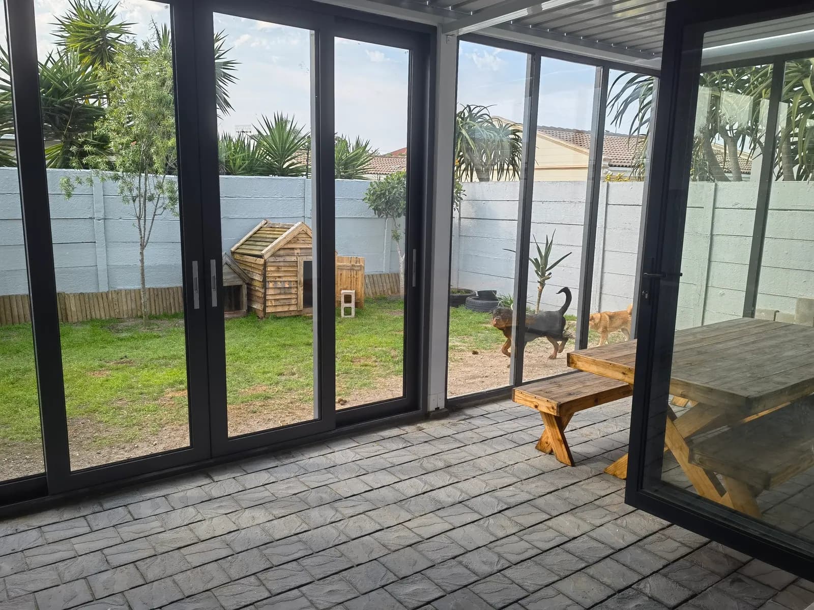 Glass sliding doors along the garden side of the pergola in daylight